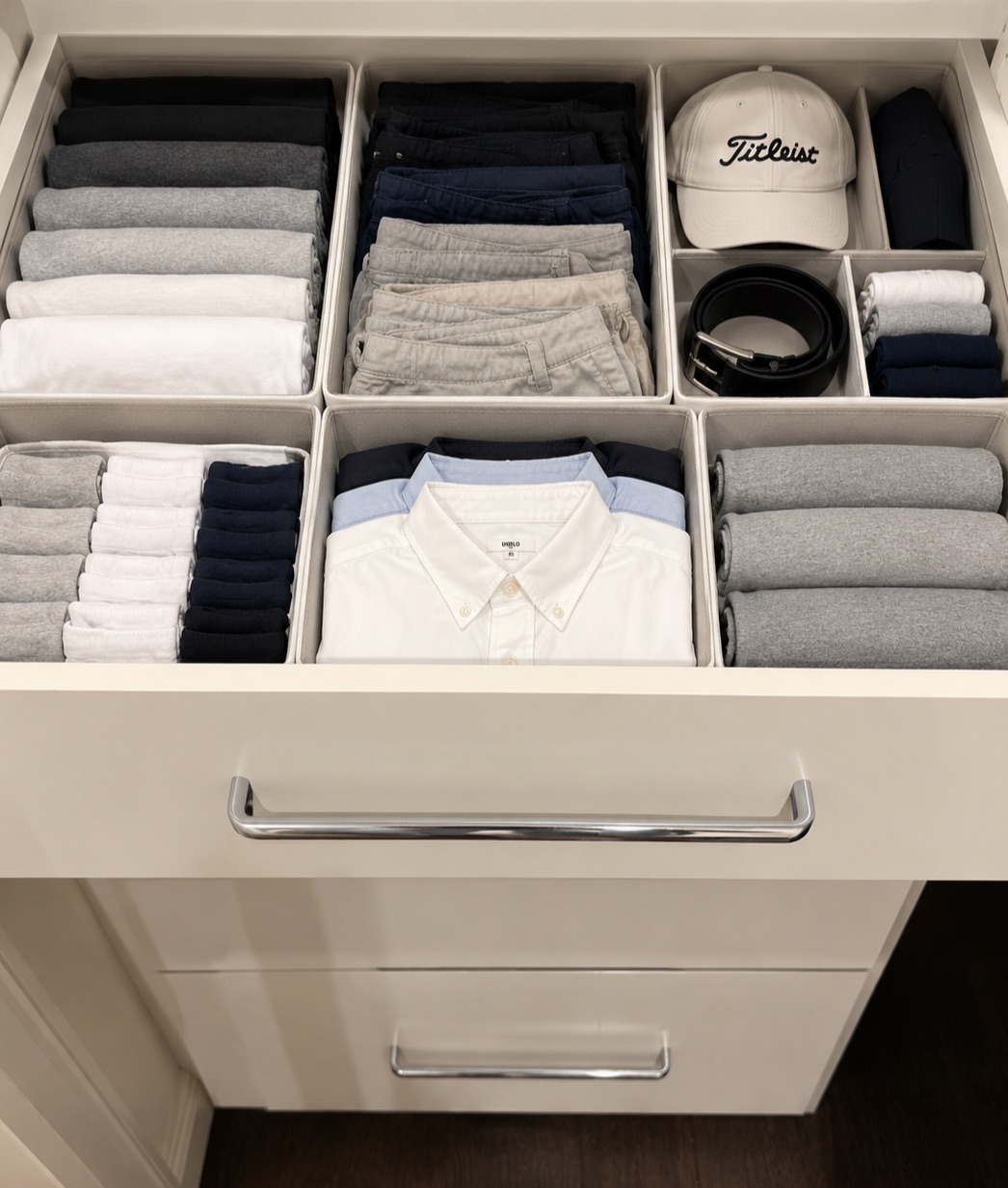 The same drawer after: six bins of shirts, chinos, socks, a cap and a belt, all folded upright